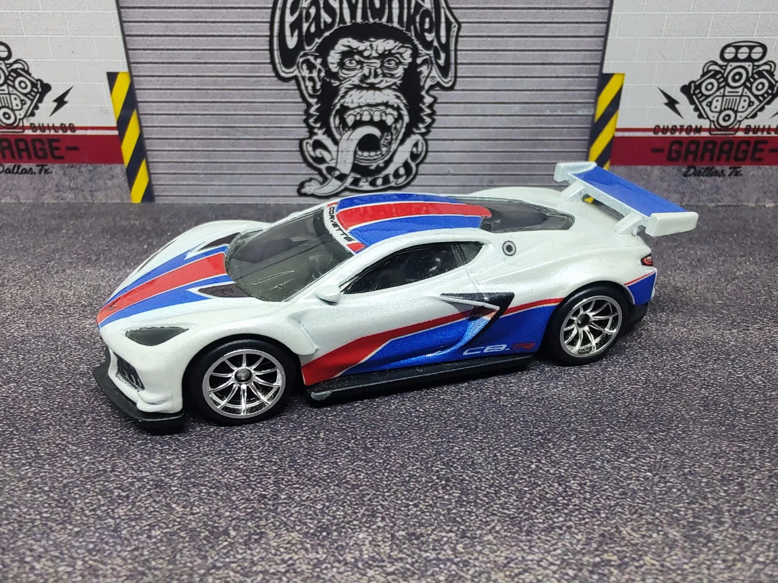 Corvette C8.R — blanco con gráficos azules y rojos, alerón blanco y llantas plateadas