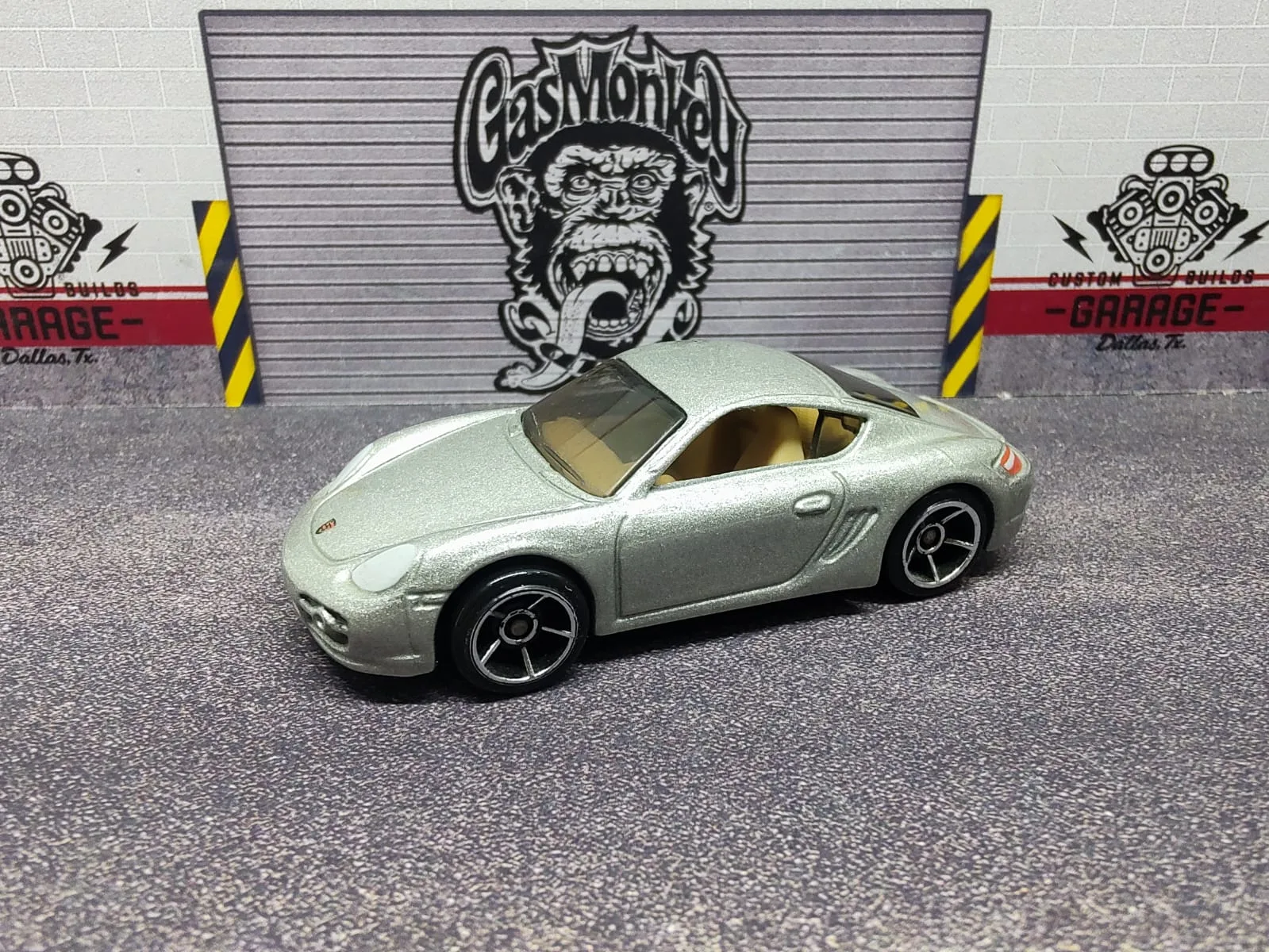 Porsche Cayman S — plateado, habitáculo claro y llantas negras con aros plateados