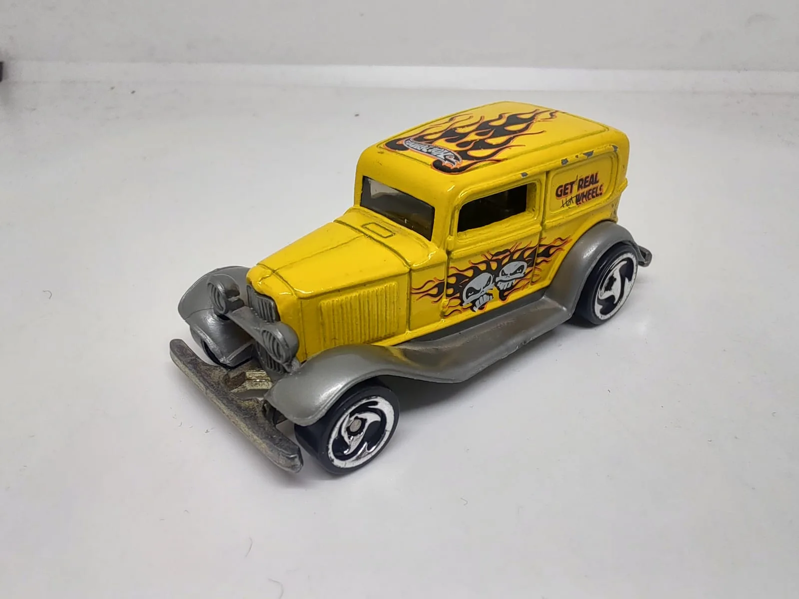 ’32 Ford Delivery — amarillo con llamas negras y texto Get Real Hot Wheels