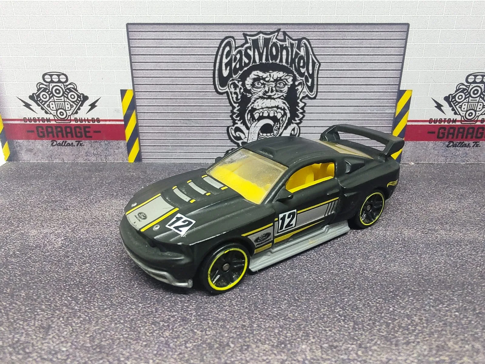 Custom ’12 Ford Mustang — gris oscuro con franjas amarillas y plateadas, interior amarillo, alerón negro y número decorativo 12
