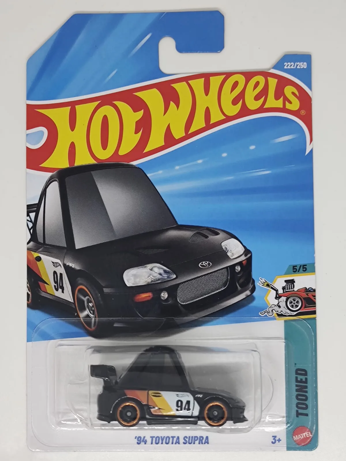 ’94 Toyota Supra (Tooned) — negro con decoración de competición y número 94; en blíster
