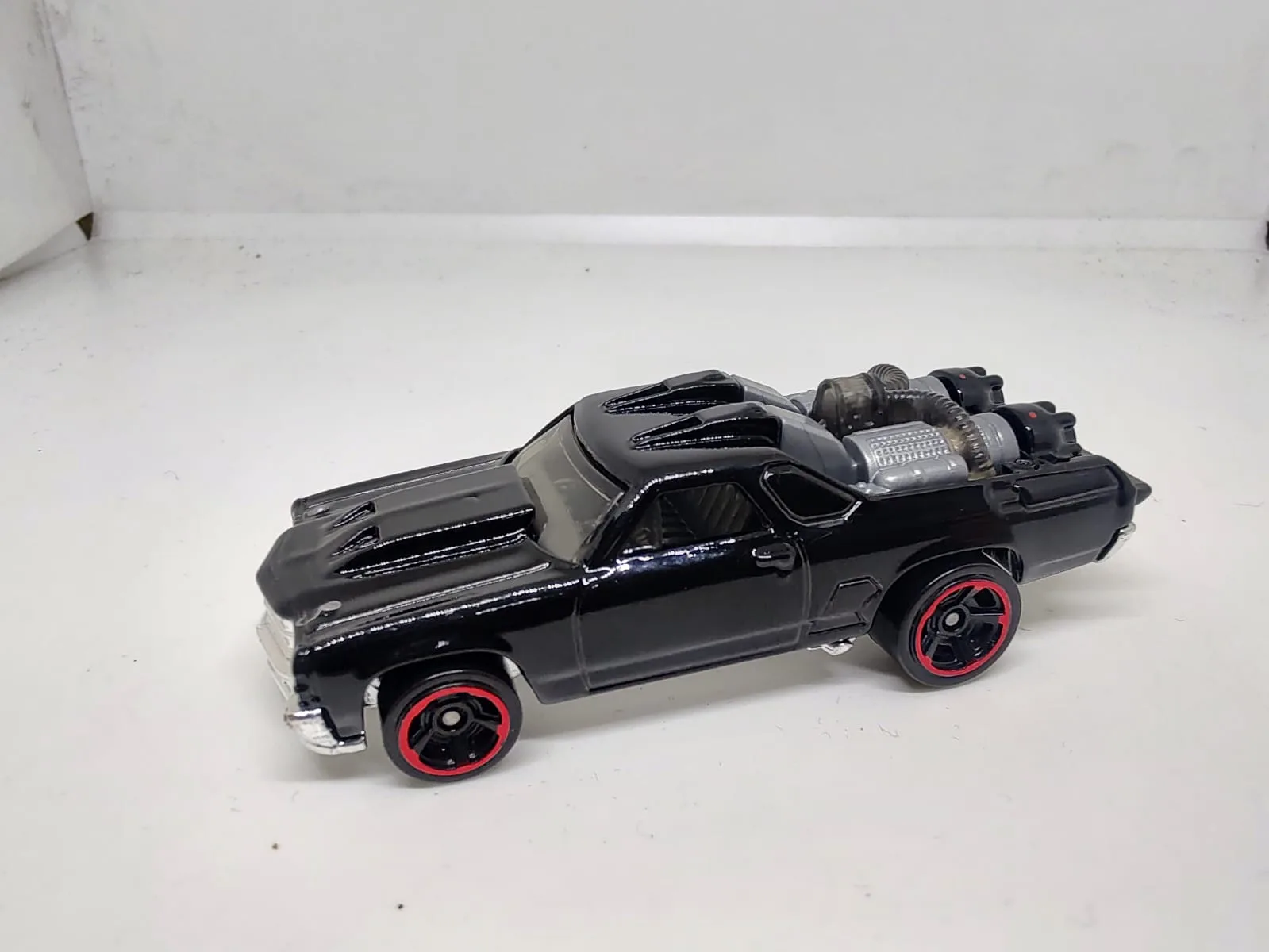 Custom ’71 El Camino — negro con motor plateado en la caja y llantas de aro rojo