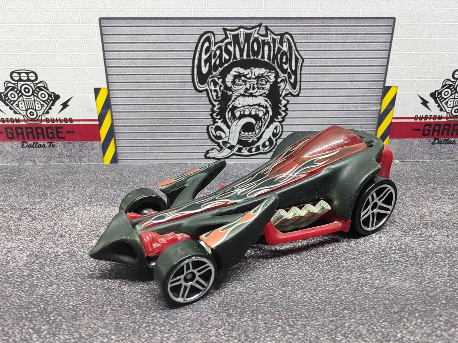 Preying Menace — hot rod de fantasía gris oscuro con llamas, tubos laterales rojos y carrocería afilada