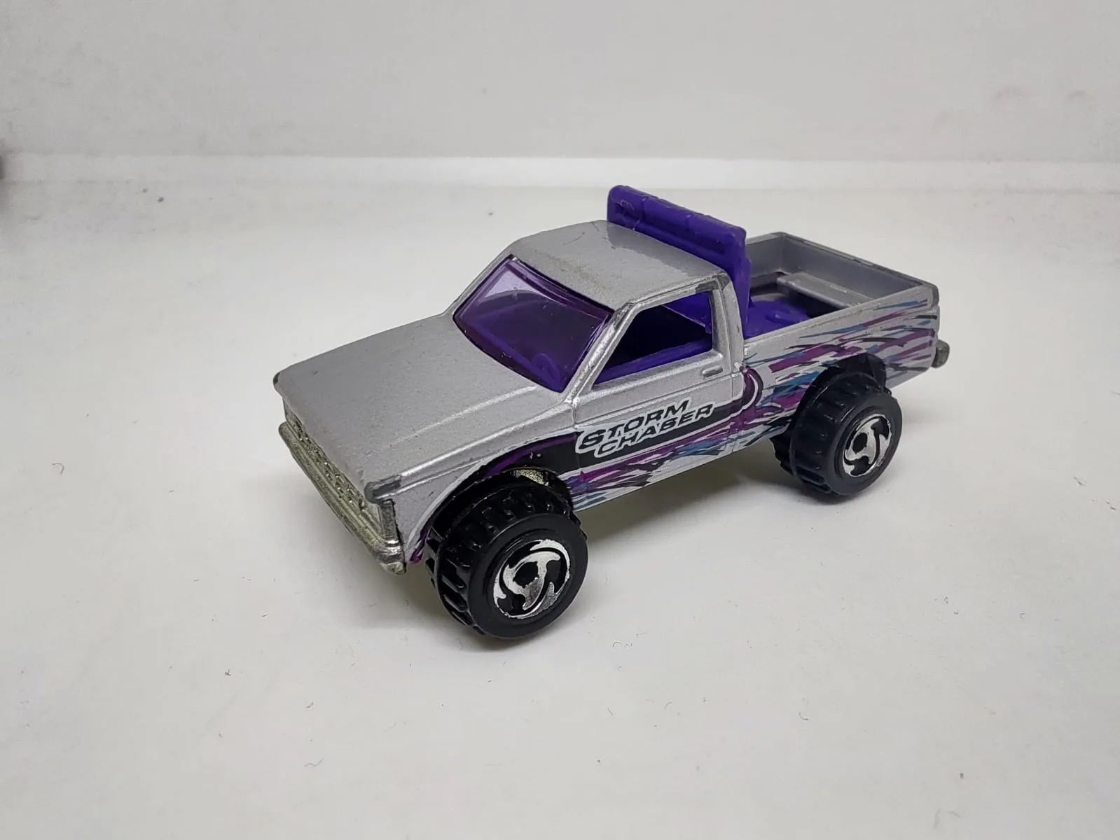 Off-Road Pickup (Surf Patrol) — pickup plateada y violeta con gráfica Storm Chaser