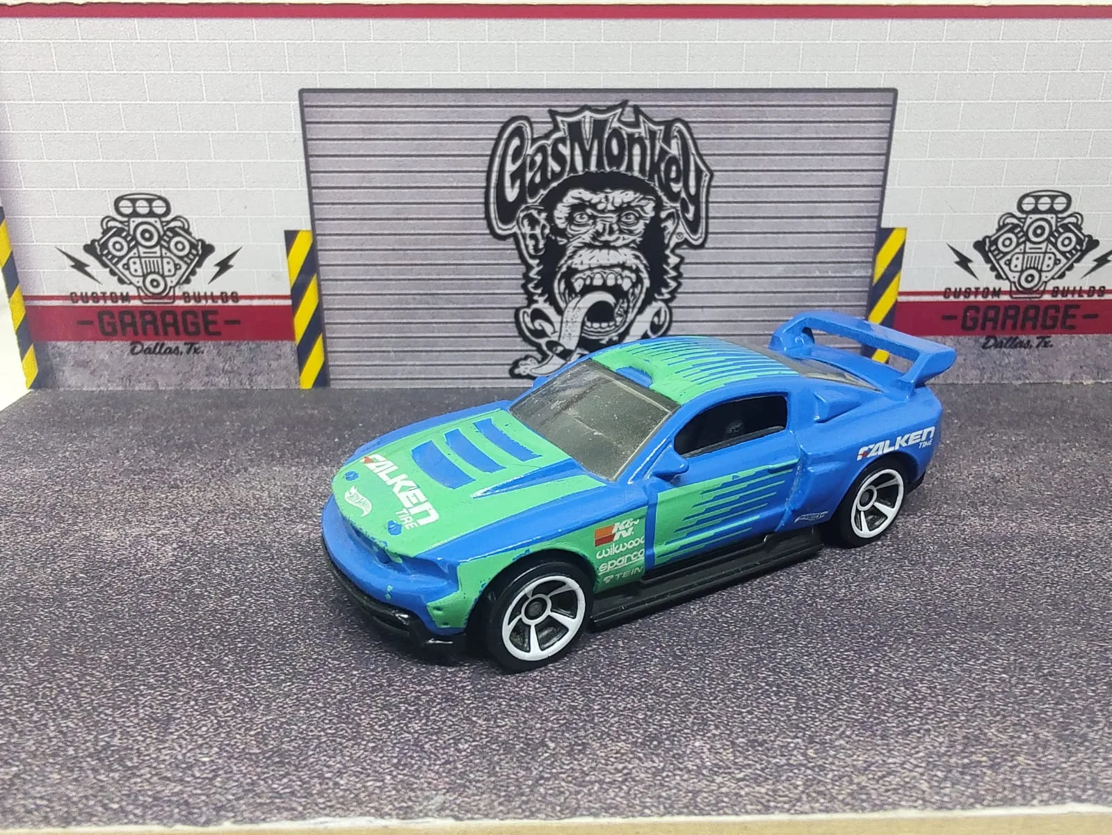 Custom ’12 Ford Mustang — azul y verde con decoración Falken, alerón azul y llantas plateadas