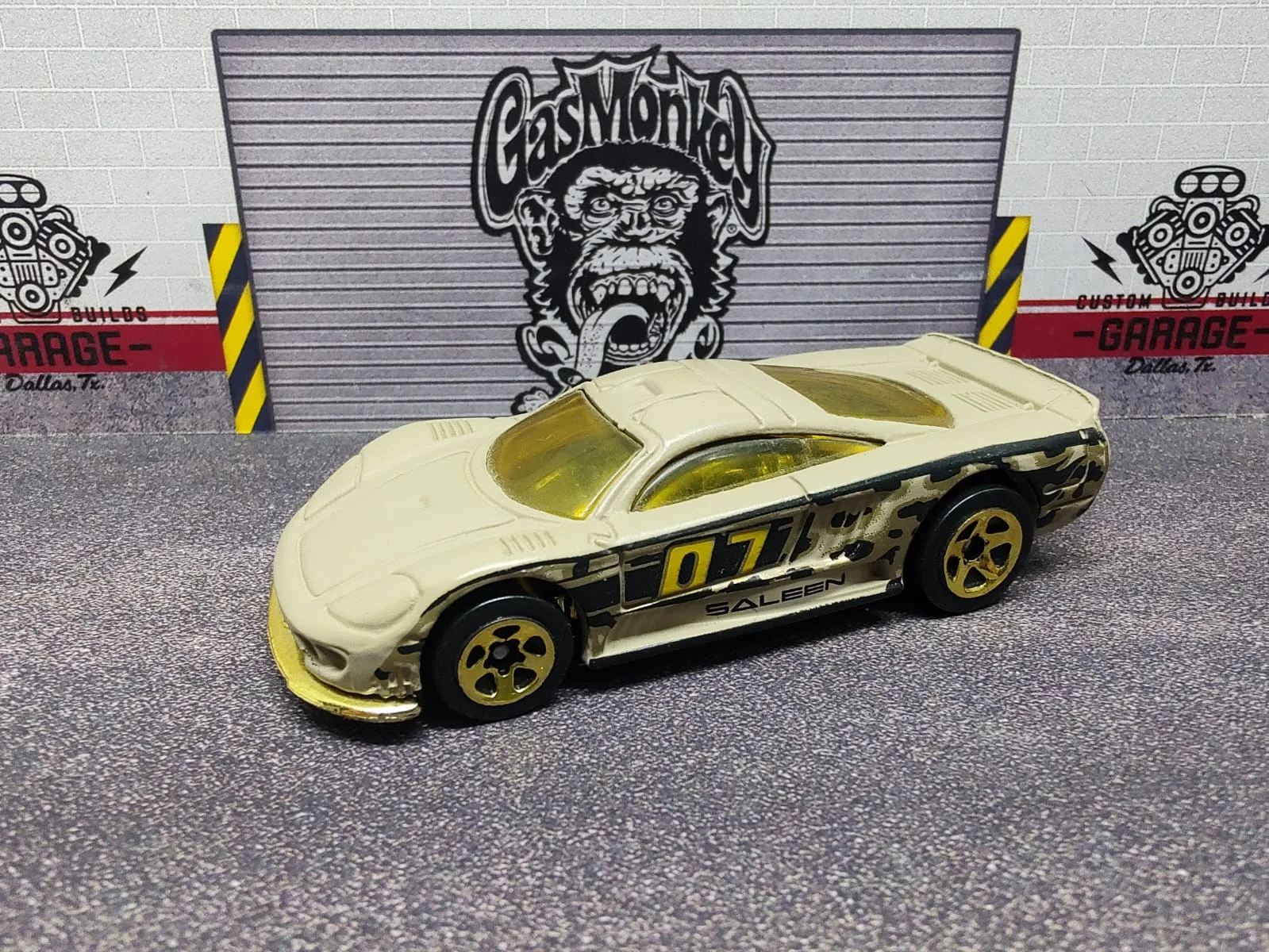 Saleen S7 — blanco crema con laterales negros, detalles dorados y número decorativo 07