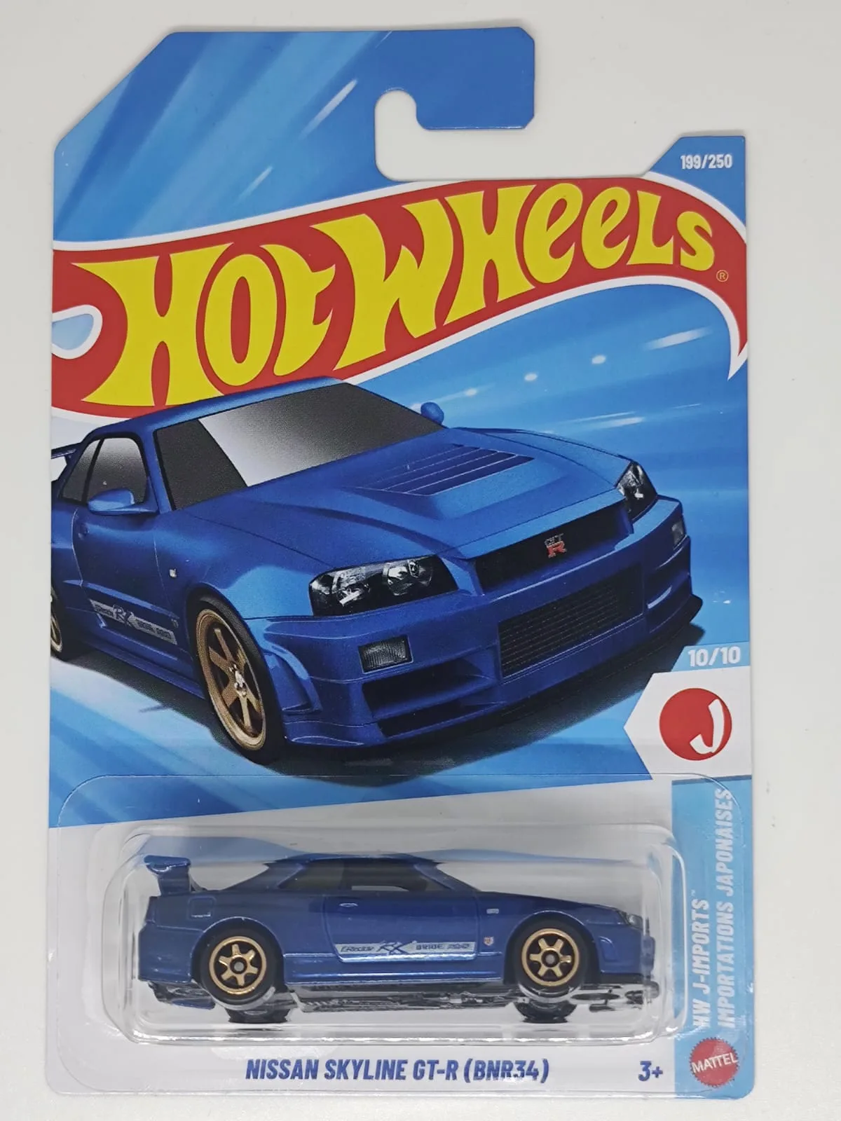 Nissan Skyline GT-R (BNR34) — azul con detalles dorados; en blíster
