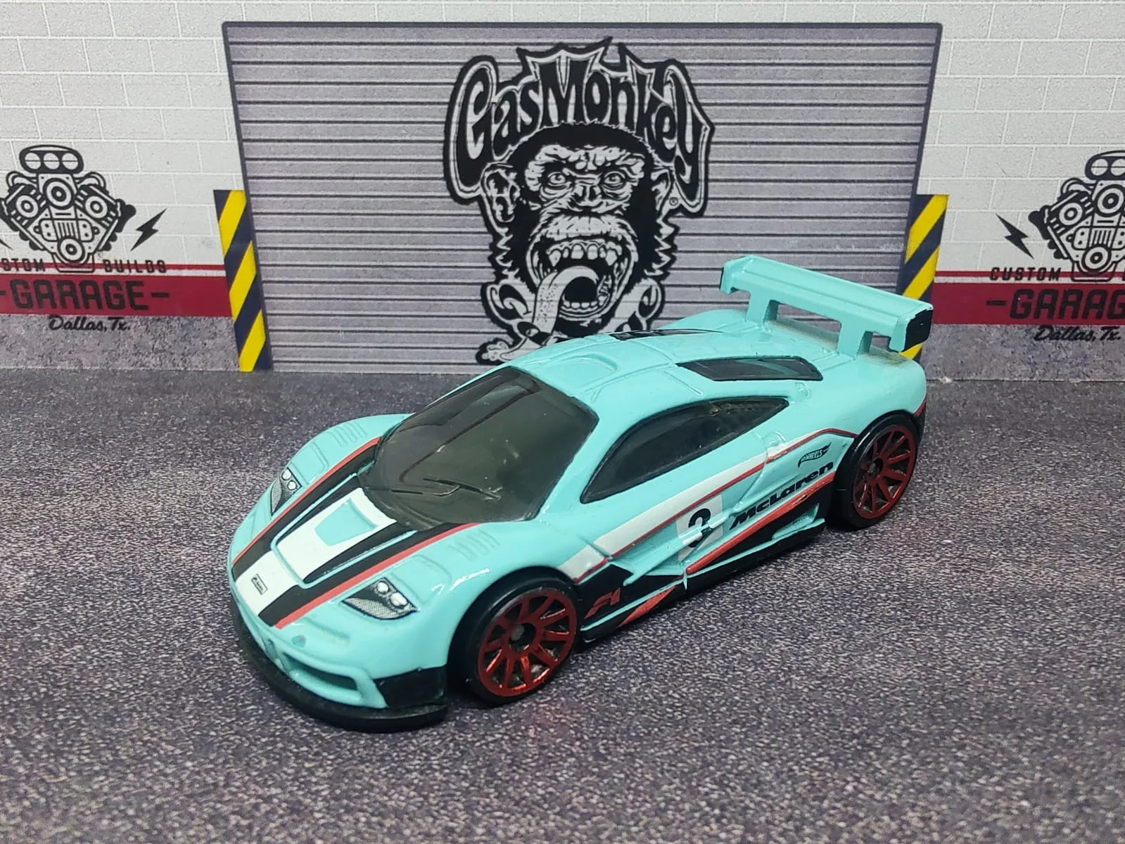 McLaren F1 GTR — turquesa claro con franjas blancas, negras y rojas, alerón y llantas de aro rojo