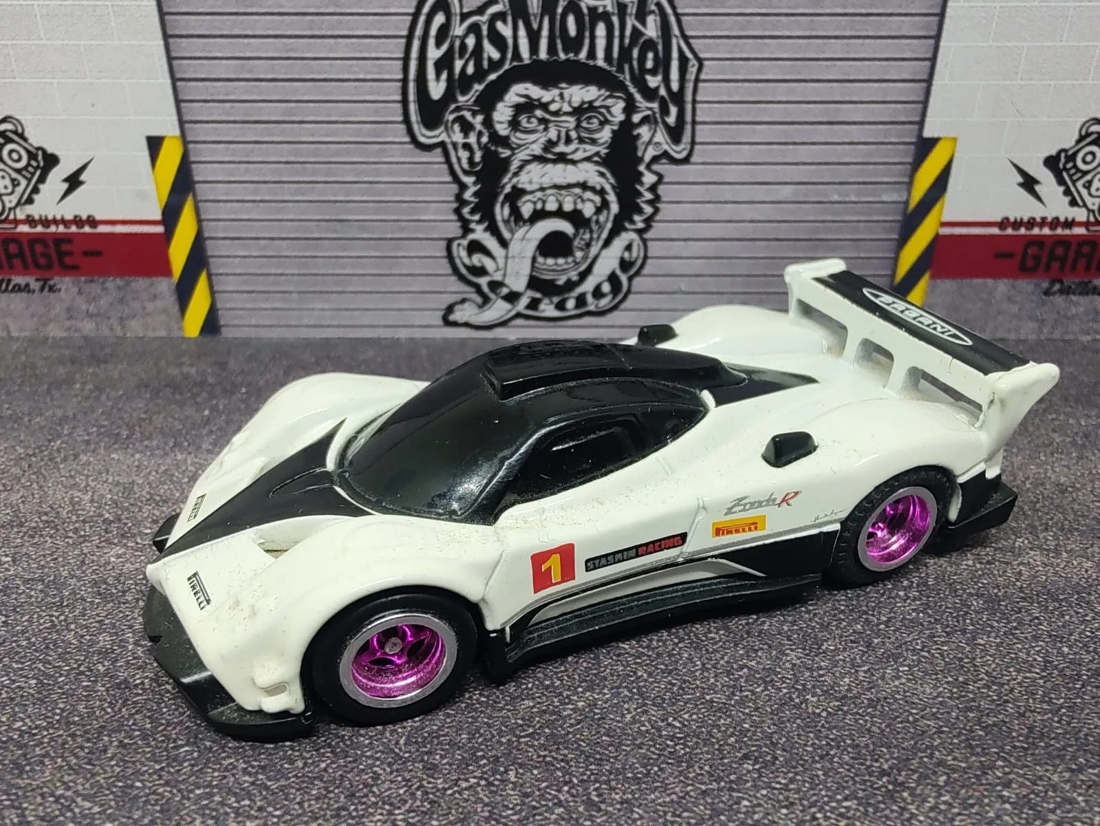 Pagani Zonda R — blanco con detalles negros y naranjas, número 1, alerón blanco y llantas violetas