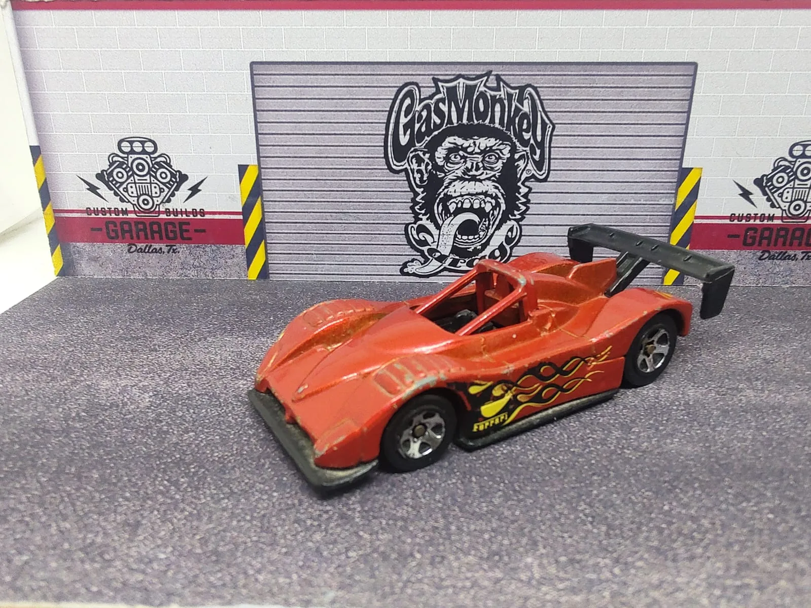 Ferrari 333 SP — rojo anaranjado con detalles amarillos y negros y alerón negro