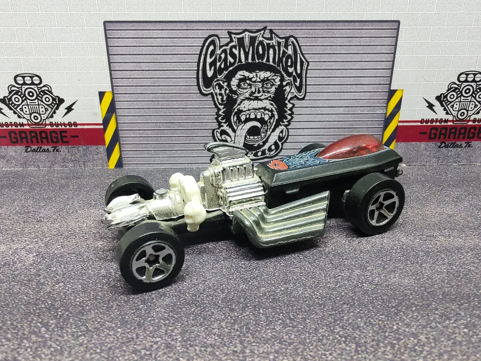 Rigor Motor — hot rod negro con forma de ataúd, asiento rojo y figura de esqueleto blanca