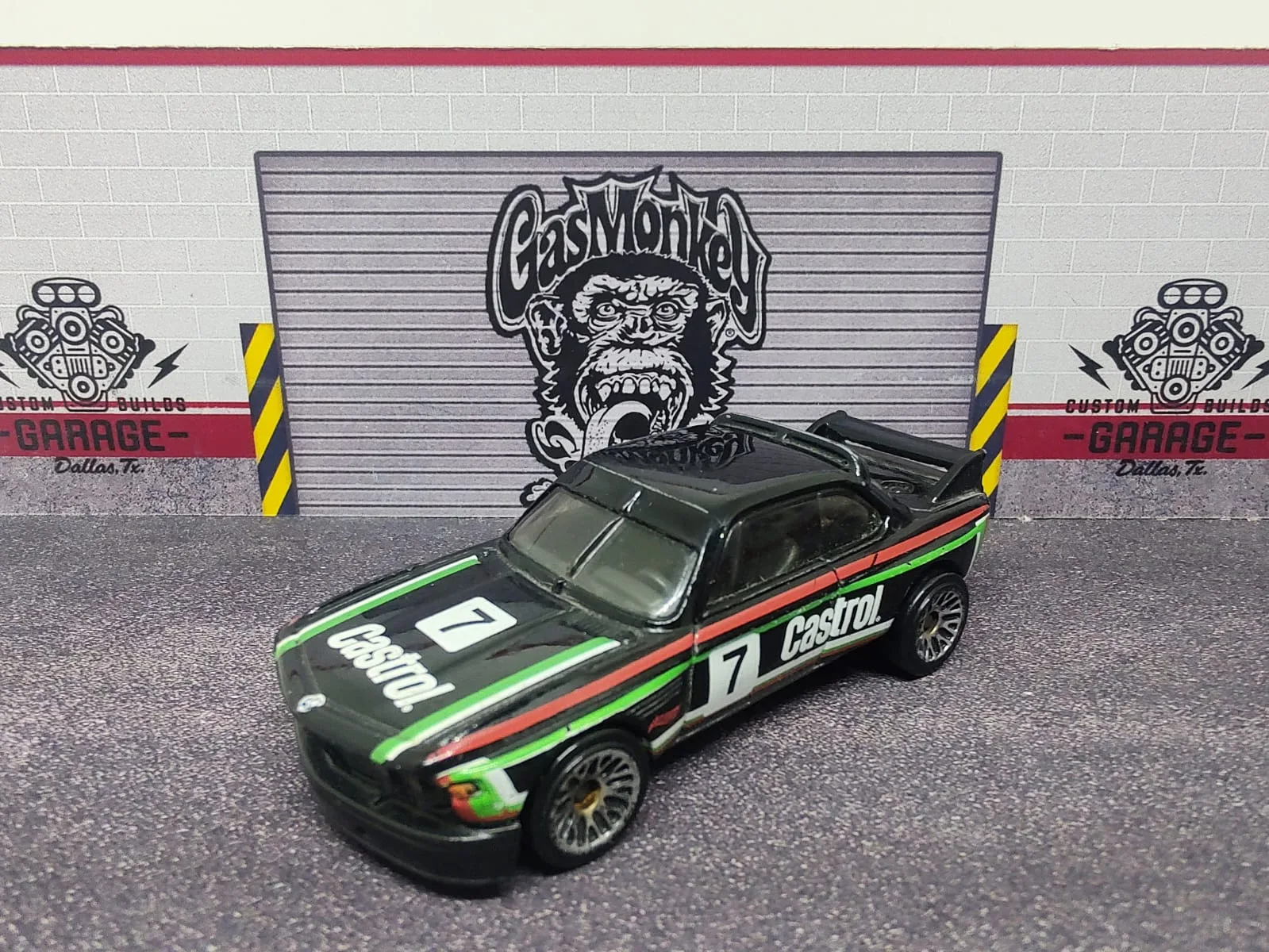 ’73 BMW 3.0 CSL Race Car — negro con franjas verdes y rojas, decoración Castrol y número decorativo 7