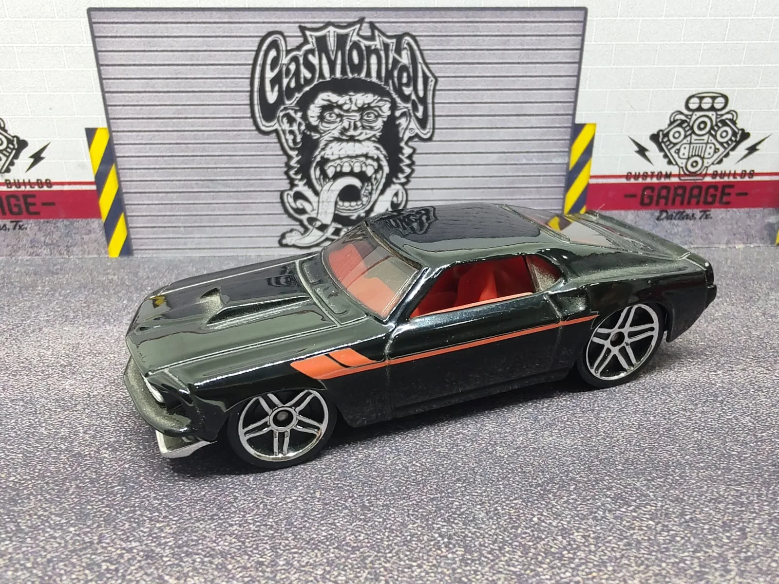 ’69 Ford Mustang — negro con franja lateral naranja e interior rojo visible